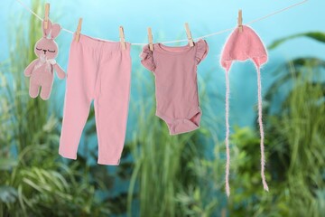 Baby clothes and bunny toy drying on laundry line outdoors
