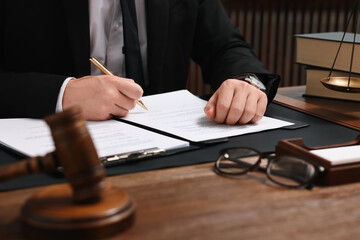 Lawyer working with documents at wooden table in office, closeup