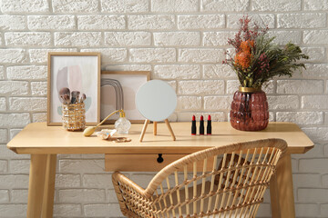 Mirror, makeup products and perfume on dressing table in room