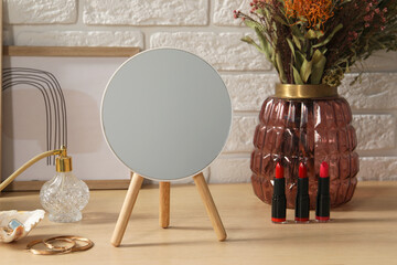 Mirror, jewelry, makeup products and perfume on wooden dressing table