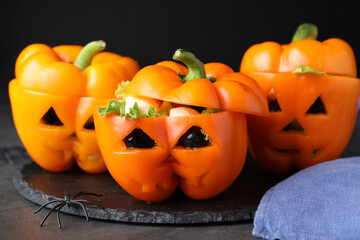 Bell peppers with black olives, mozzarella and lettuce as Halloween monsters on dark table, closeup