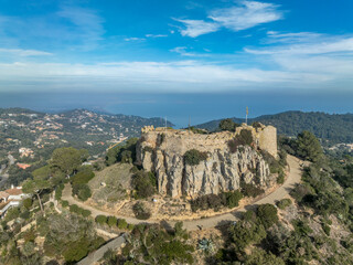 Fototapeta na wymiar Aerial view of 16th-century Begur castle fort atop a forested hill, with panoramic views of the Mediterranean Sea. Watch towers built against the pirates