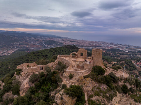 Aerial sunset view of the remains of a small, 11th-century Burriac castle, chapel on a hill, with a modest hike and dramatic views