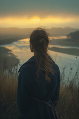 A woman watching sunset over river