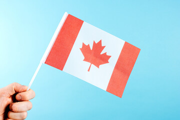 Hand Holding Canadian Flag on Blue Background