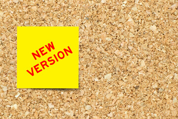 Yellow note paper with word new version on cork board background with copy space