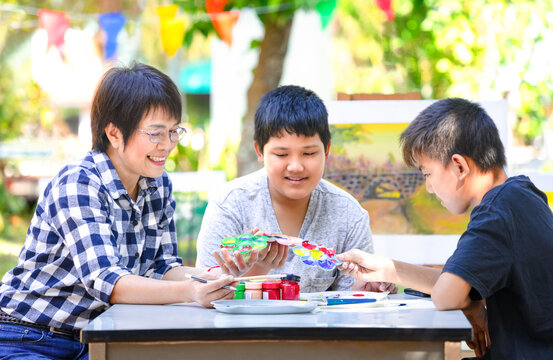 middle age asian woman enjoy teaching the young teens student at school outdoors, happy female teacher helps teenage pupils painting in art class