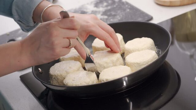 Cooking fried quark pancakes Syrniki. Pancakes are fried in a frying pan. Belarusian, Russian, Ukrainian cuisine.