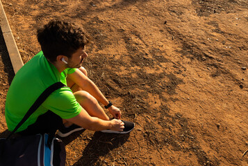 Young fit sportsman with a gym bag ties his shoelaces. Concept active lifestyle.