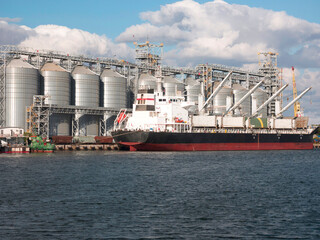 Loading grain onto a ship in the port. Grain terminal at the port. Logistics in grain trade.