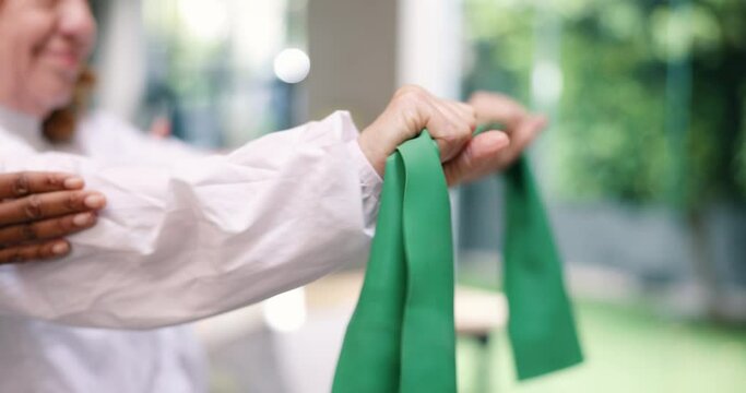 Old person, arms and stretching in retirement resistance band for mobility, health or exercise. Elderly woman, hands and helper for rehabilitation performance in garden, training or physical therapy