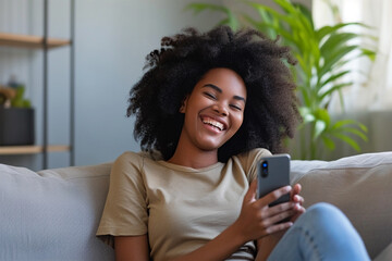 Young woman sitting in sofa smiling looking at phone