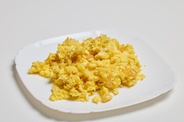 a plate of scrambled eggs on a table ready to be eaten.