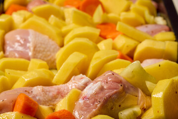 chicken legs with potatoes, carrots, bell pepper prepared to be cooked in the oven.