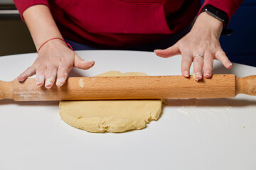 The hands of a woman preparing a traditional homemade dough cake in the kitchen.