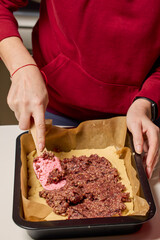 The hands of a woman preparing a traditional homemade dough cake in the kitchen.