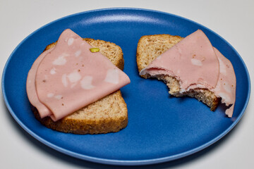 slices of bread with mortadella on a plate.