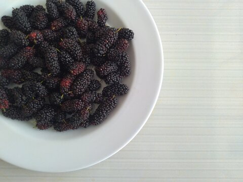 a bunch of ripe mulberries in white plate