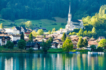 Swiss village Lungern with traditional houses, old church Alter Kirchturm along lovely emerald...