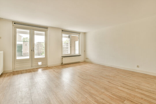 Bright empty room with wooden floor and large windows