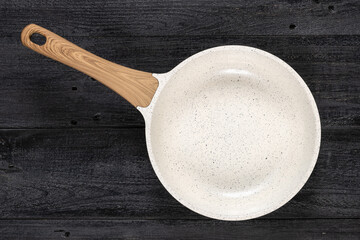 Round fry pan on a weathered black wood texture background. Non-stick, ceramic coated cooking technology.