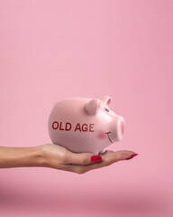 Piggy bank in a woman hand with inscription OLD AGE on a pink background. Minimal saving money concept.