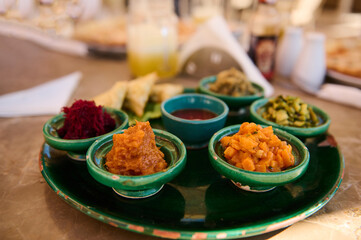 Food background traditional Moroccan salads served on tagine dishes on green ceramic plate. Moroccan culture, cuisine