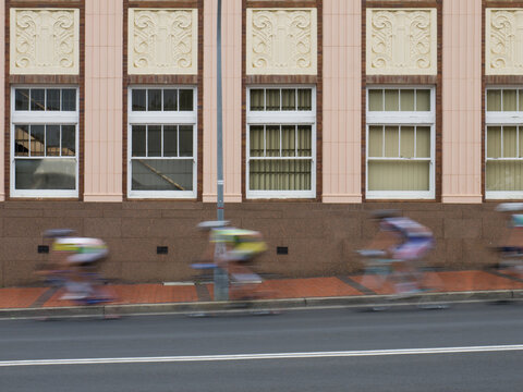 Cyclists racing on a road past an office building