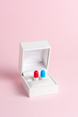 Creative composition with red and blue pill in engagement ring box on blue background. Minimal...