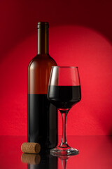 Bottle of red wine with wine glass and cork on table. Drink concept.