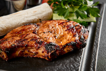 Grilled pork loin with fresh vegetables, lavash, and sauces on a slate plate