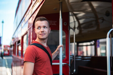 Portrait of tourist boarding to red double-decker bus in central London. United Kingdom..