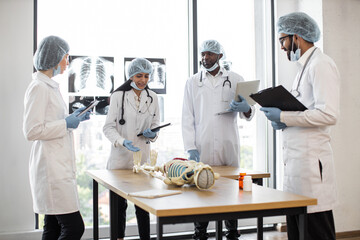 University, education, medicine, anatomy concept. Multiracial medical students in protective masks,...