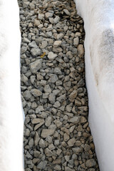 The drainage trench is covered with geotextile and filled with crushed stone to drain ground water...