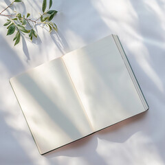 Open diary or planner with empty blank pages, lying on a gentle white silk or satin fabric. Minimalism