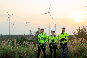 Group of technician workers stand with arm crossed and look to left side in front of windmill or...