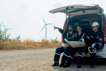 Side view group of technician workers sit on back of van and discuss about work in plan paper on...