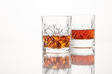 Whiskey, scotch is poured into two crystal glasses.