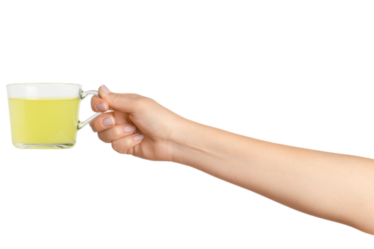 A woman's hand holds a cup of green herbal tea in a transparent glass cup. On a blank background