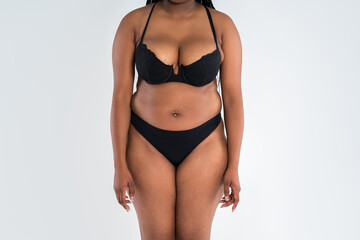 Curvy busty plus size model in push up bra on gray background, overweight African black woman in...