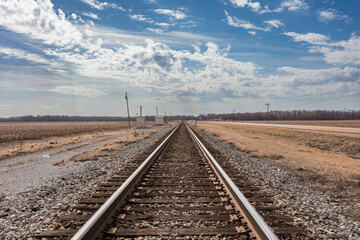 train tracks vanishing into the distance cutting through the middle of cotton fields - 715651968