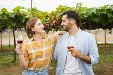 Happy vineyard - grape yard farmers tasting a wine or grape juice together while standing in the vineyard. Lovely couple taste a wine - grape juice in the vineyard.