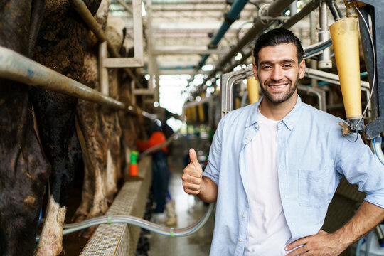 Happy cheerful Middle East - Asian male farmer collecting a dairy milk and smiling to camera.