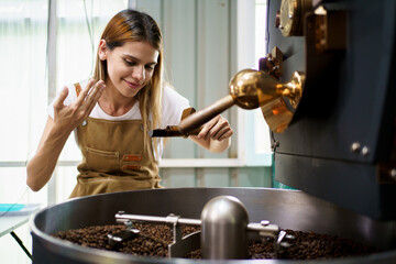 Professional coffee roaster working with modern automated roasting machine in the coffee roasting factory. 
