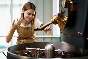 Professional coffee roaster working with modern automated roasting machine in the coffee roasting...