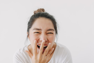 Happy asian Thai woman hand covering mouth while laughing, feeling glad and joyful, wear white and bun hairstyle, standing isolated over white background wall.