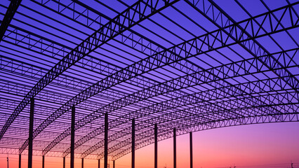 Silhouette curve metal roof beam with columns of large factory building outline structure in construction site against colorful twilight sky background, low angle and inside view - Powered by Adobe
