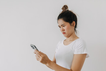 Asian Thai woman using mobile phone and looking with funny doubt face, holding smartphone by silent suspicious, standing isolated over white background wall.