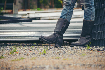 Legs of Lonely man wearing jeans and leather boots walking along the path strewn with rocks. Travel Concept.