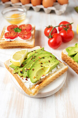 Fototapeta na wymiar Sliced avocado on toast bread with spices on white wooden background. Food concept.